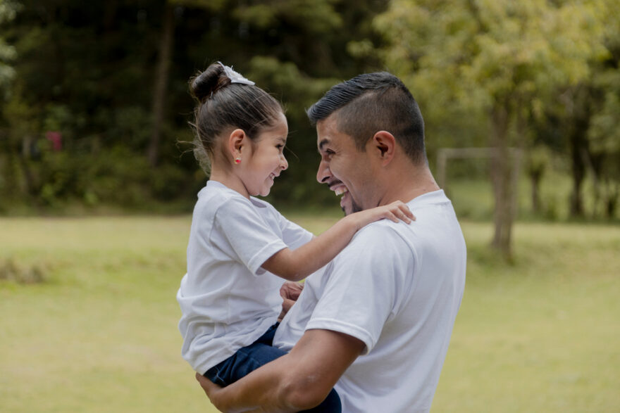 Dad and daughter hugging and smiling in the park