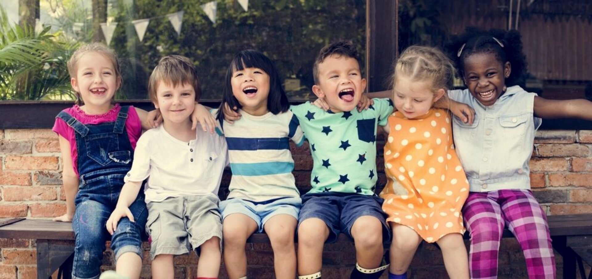 Group of multiethnic children on bench smiling and hugging